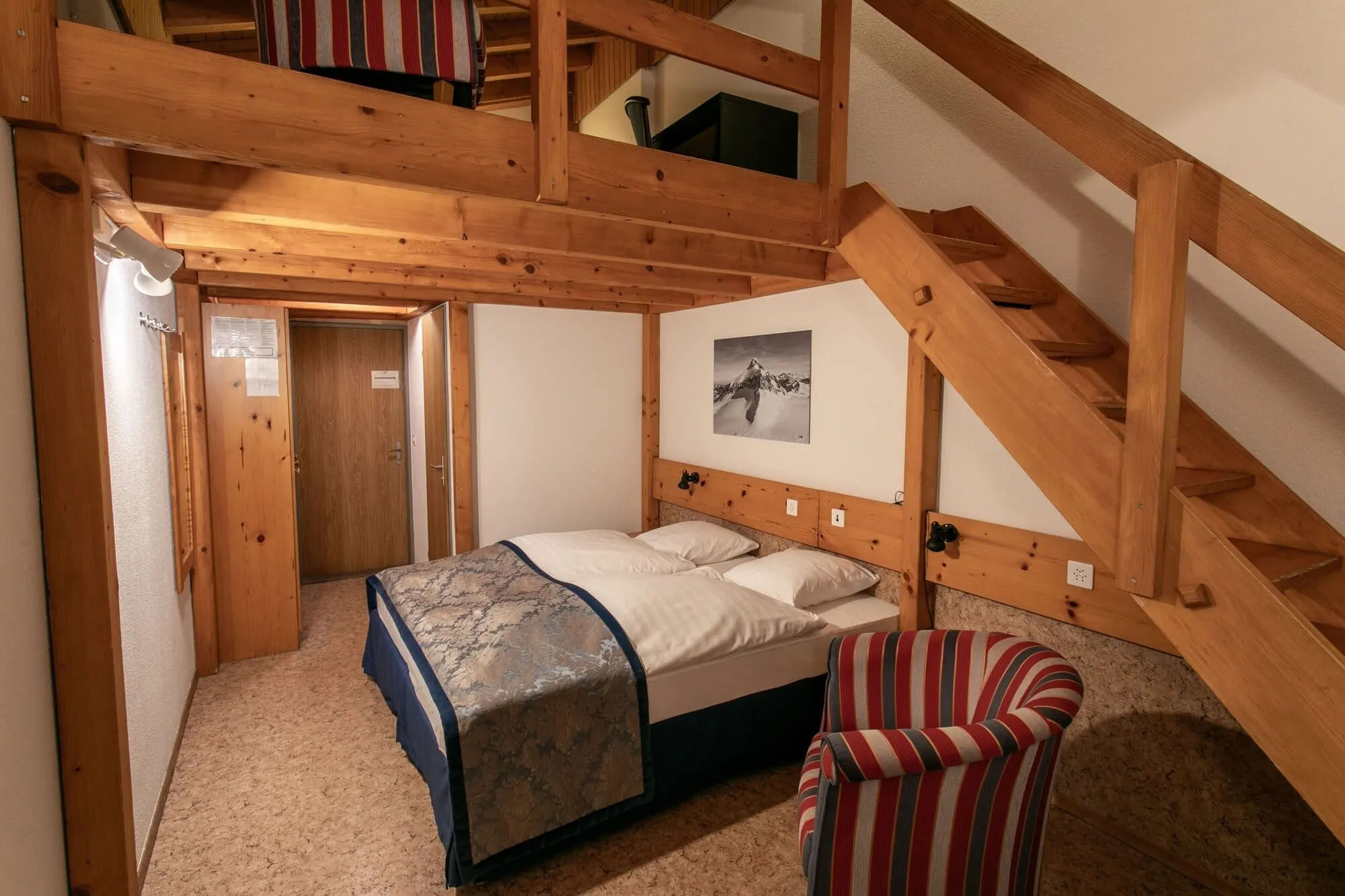 A duplex room with a wooden staircase